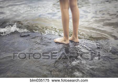 Stock Photography - Caucasian girl standing in ocean waves. Fotosearch