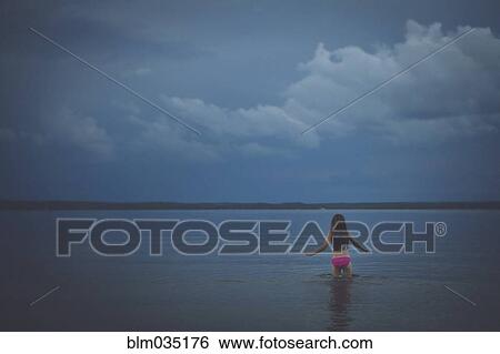 Stock Photograph - Caucasian girl wading in remote lake. Fotosearch