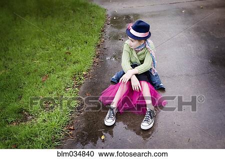 Stock Image - Caucasian girl wearing sneakers and tutu in puddle. Fotosearch