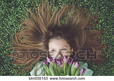 Caucasian girl with tulips laying in grass View Large Photo Image Stock Image - Caucasian girl with tulips laying in grass. Fotosearch