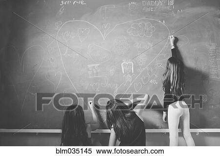 Stock Photography - Caucasian girls drawing on classroom chalkboard. Fotosearch