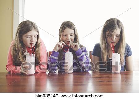 Caucasian girls drinking milk with curled straws at table View Large Photo Image Stock Photo - Caucasian girls drinking milk with curled straws at table. Fotosearch