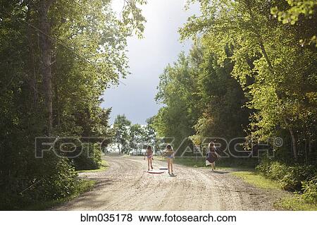 Stock Photo - Caucasian girls walking on dirt road. Fotosearch