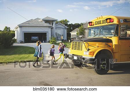 Stock Image - Caucasian girls walking to school bus. Fotosearch