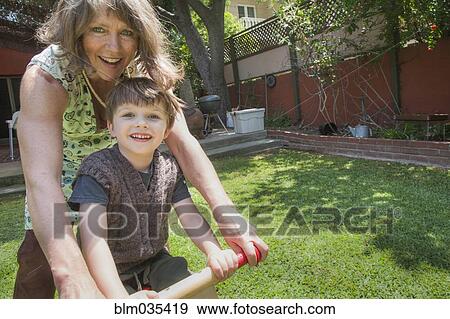 Caucasian grandmother and grandson riding bicycle in backyard View Large Photo Image Stock Photo - Caucasian grandmother and grandson riding bicycle in backyard. Fotosearch