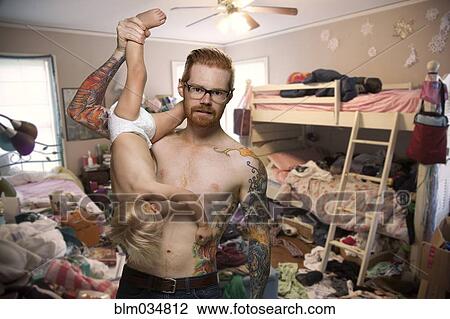 Stock Image - Caucasian man holding baby son in messy bedroom. Fotosearch