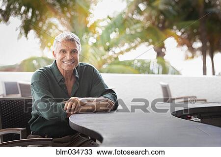 Stock Image - Caucasian man sitting at patio bar. Fotosearch