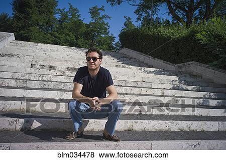 Stock Photo - Caucasian man sitting on staircase outdoors. Fotosearch