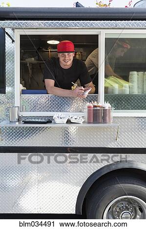 Stock Image - Caucasian man working in food truck. Fotosearch