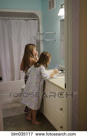Stock Photo - Caucasian sisters brushing teeth in bathroom. Fotosearch