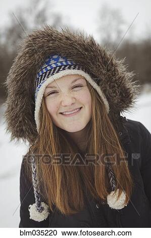 Stock Image - Caucasian teenage girl wearing fur coat and hat in snow. Fotosearch