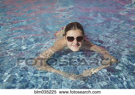 Stock Photography - Caucasian teenage girl wearing sunglasses in swimming pool. Fotosearch