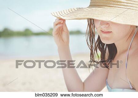 Stock Photo - Caucasian teenage girl wearing sun hat on beach. Fotosearch