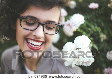 Stock Photography - Caucasian woman admiring flowers on shrub. Fotosearch