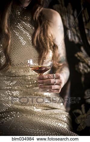 Picture - Caucasian woman in evening gown drinking cocktail. Fotosearch