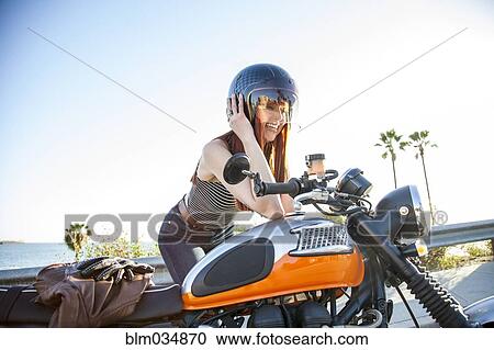 Stock Image - Caucasian woman in helmet sitting on motorcycle. Fotosearch