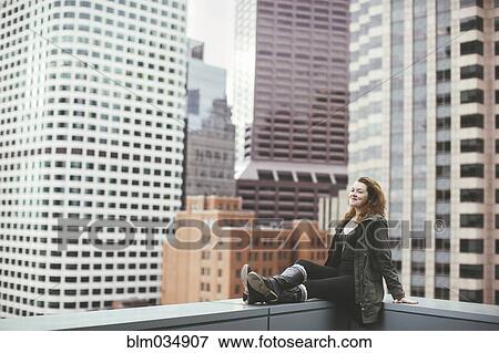 Stock Photo - Caucasian woman on urban rooftop admiring cityscape. Fotosearch