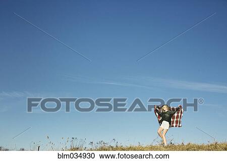 Stock Image - Caucasian woman playing with scarf on hilltop. Fotosearch