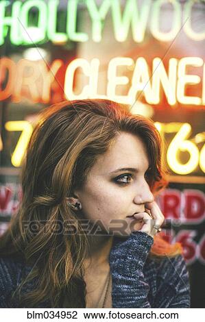 Stock Image - Caucasian woman standing in front of neon sign. Fotosearch