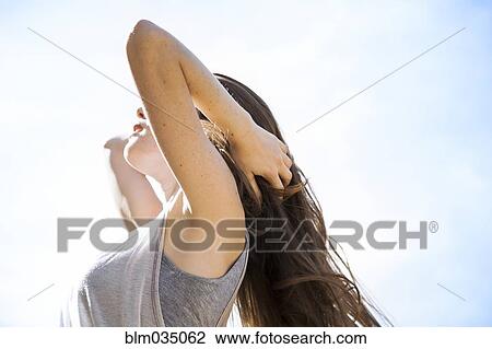 Stock Image - Caucasian woman standing under blue sky. Fotosearch