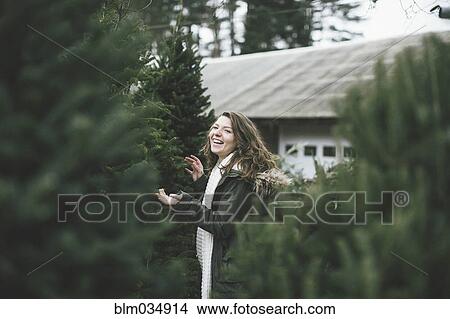 Picture - Caucasian woman walking in Christmas tree lot. Fotosearch