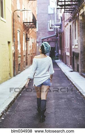 Caucasian woman walking in urban alleyway View Large Photo Image Stock Photo - Caucasian woman walking in urban alleyway. Fotosearch