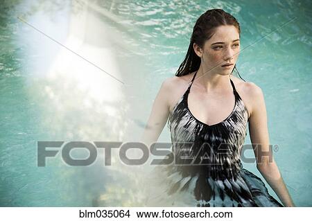 Picture - Caucasian woman wearing dress in swimming pool. Fotosearch