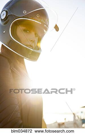 Stock Image - Caucasian woman wearing motorcycle helmet. Fotosearch