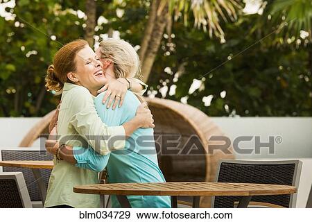 Stock Photo - Caucasian women hugging on restaurant patio. Fotosearch