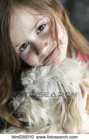 Stock Image - Close up of Caucasian girl hugging puppy. Fotosearch