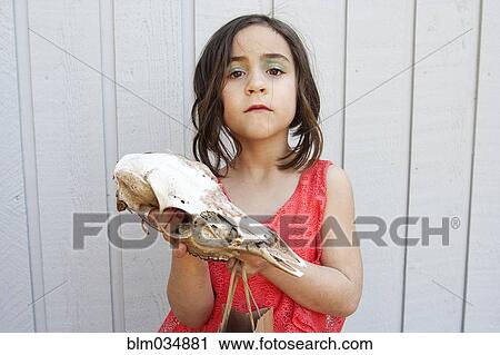 Stock Image - Close up of girl holding animal skull. Fotosearch