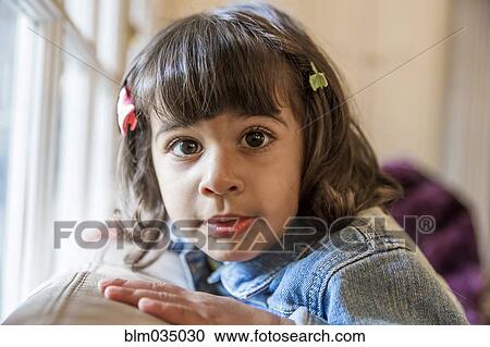 Stock Image - Close up of girl sitting on sofa. Fotosearch