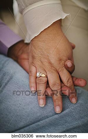 Stock Photograph - Close up of husband and wife holding hands. Fotosearch