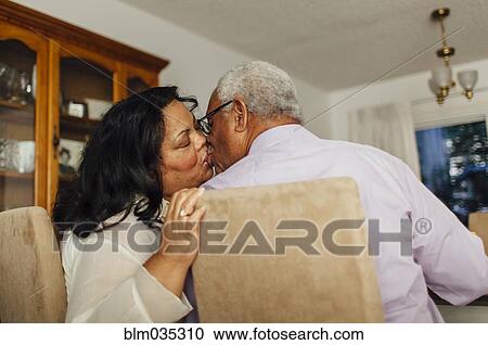 Stock Image - Close up of kissing couple in dining room. Fotosearch