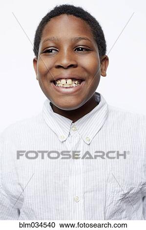Stock Image - Close up of smiling boy wearing fully-buttoned shirt. Fotosearch