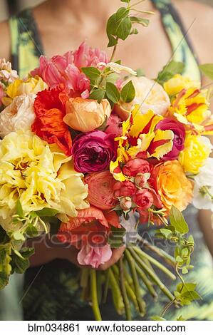 Stock Image - Close up of woman holding bouquet of flowers. Fotosearch