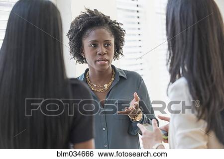 Stock Photograph - Concerned businesswomen talking in office. Fotosearch