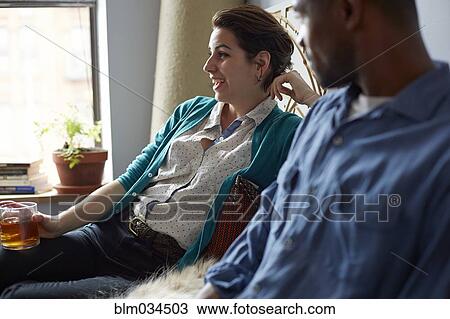 Stock Image - Couple drinking tea in living room. Fotosearch