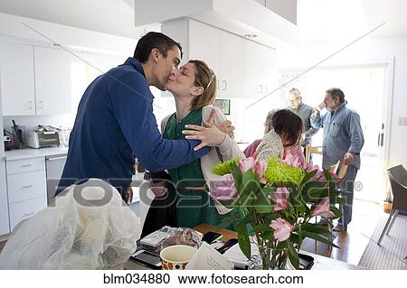 Stock Image - Couple kissing in kitchen. Fotosearch