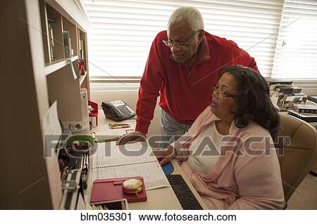 Stock Image - Couple using computer in home office. Fotosearch