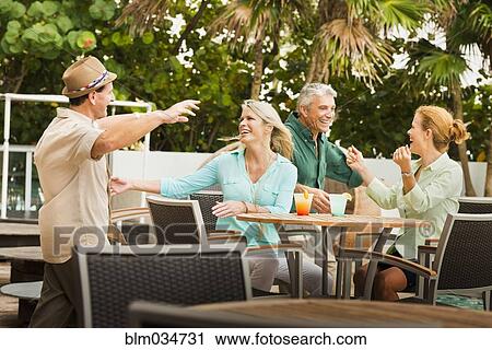 Stock Image - Couples hugging on restaurant patio. Fotosearch
