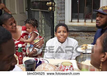 Stock Photography - Family eating together at backyard barbecue. Fotosearch