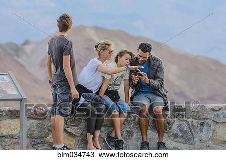 Stock Image - Family using cell phone at national park. Fotosearch