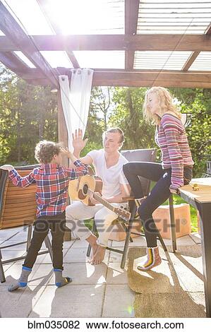 Father and son high-fiving on backyard patio View Large Photo Image Stock Image - Father and son high-fiving on backyard patio. Fotosearch
