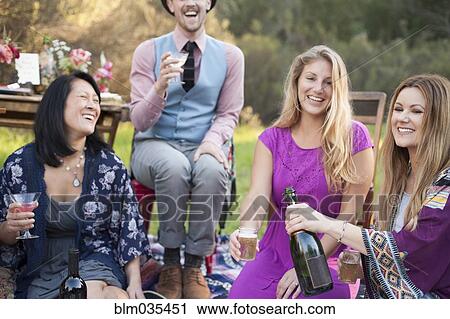 Stock Image - Friends drinking champagne at picnic in park. Fotosearch