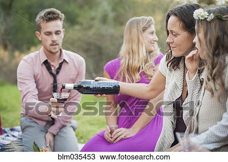 Stock Image - Friends drinking wine at picnic in park. Fotosearch