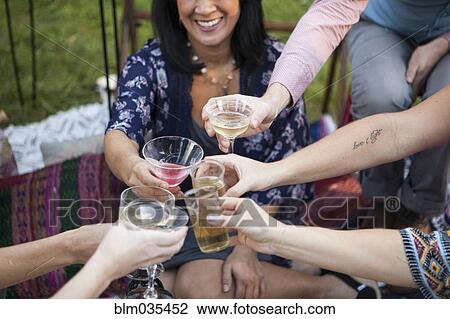 Stock Image - Friends toasting with champagne at picnic in park. Fotosearch