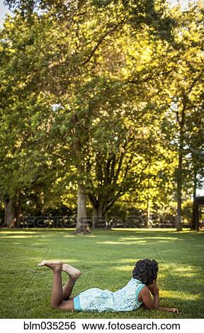 Girl laying in grass in park View Large Photo Image Stock Photograph - Girl laying in grass in park. Fotosearch