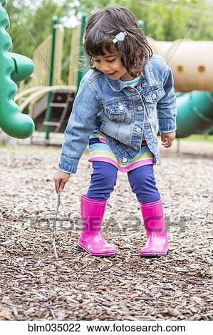 Stock Image - Girl playing with stick at playground. Fotosearch