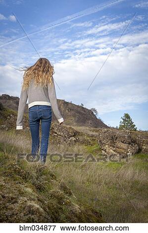 Girl walking on grassy hillside View Large Photo Image Stock Photo - Girl walking on grassy hillside. Fotosearch